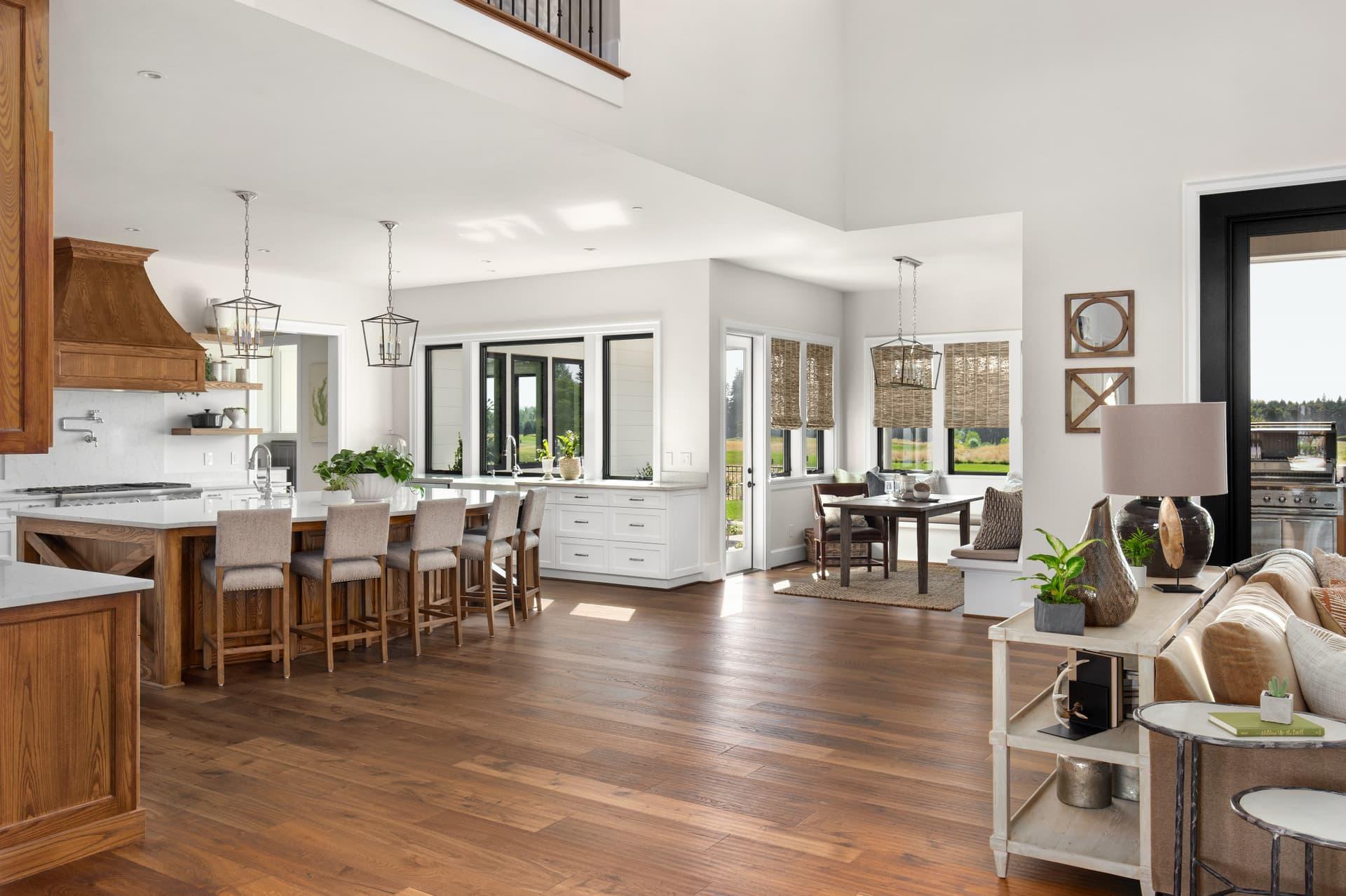 Open-concept kitchen with a long island, wood range hood and hardwood floors beside a dining and living area