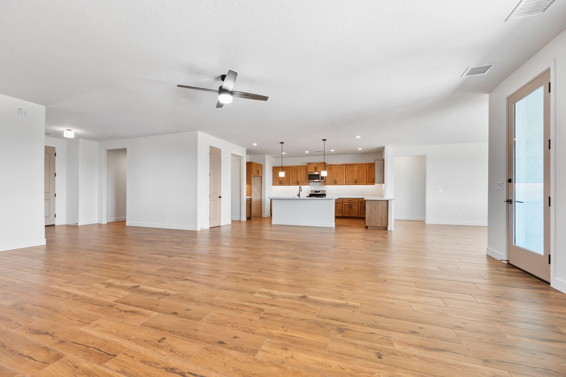 Empty open-concept main floor with hardwood flooring and a kitchen at the far end