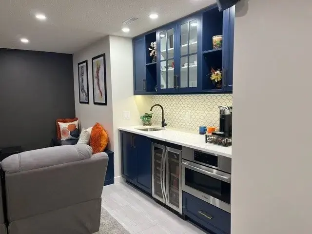 Basement wet bar after renovation with navy cabinetry and wine fridge